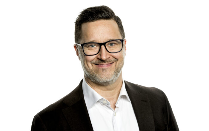 Profilbild på Jon Forsell. Jon har på sig svart kavaj och vit skjorta. Han bär glasögon, ler och tittar in i kameran.
